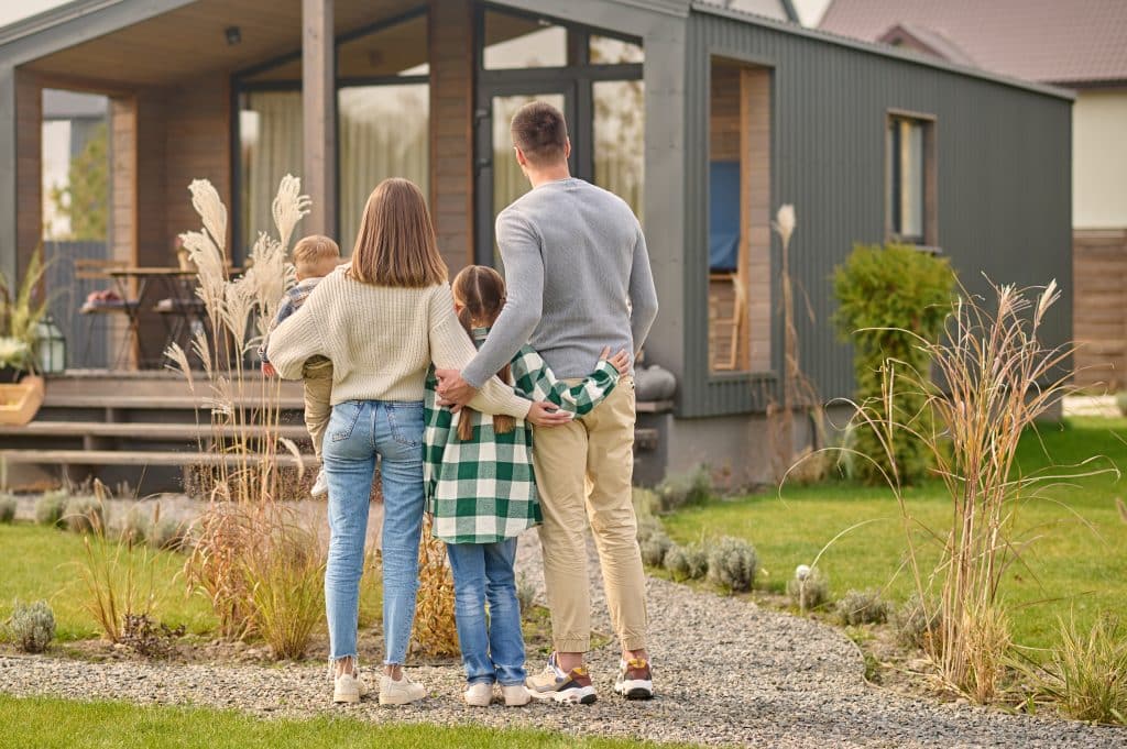 Home back view of family hugging and admiring their home